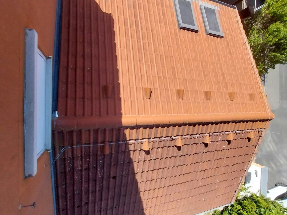 Pohled z výšky na vyčištěnou betonovou krytinu domu se dvěma střešními okny